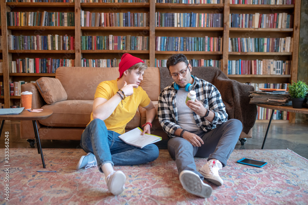 Dark-haired man in eyeglasses discussing new pills with his friend Dark-haired man in eyeglasses discussing new pills with his friend