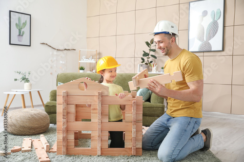 Fotografia Father and little daughter dressed as builders playing with take-apart house at