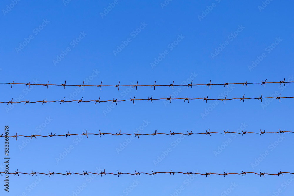 Barbed wire against a blue sky background Barbed wire against a blue sky background
