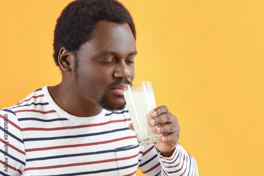 Young African-American man with milk on color background Young African-American man with milk on color background
