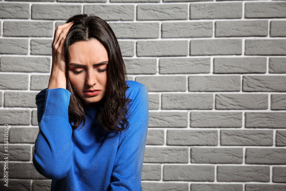 Depressed young woman near brick wall Depressed young woman near brick wall