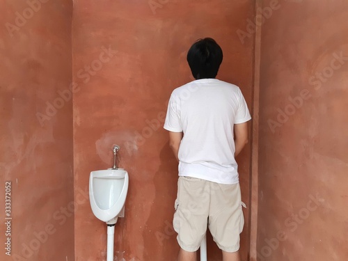 man standing and peeing in front of a toilet