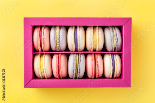 Colorful macaroons and flowers. Sweet macarons in gift box. Top view