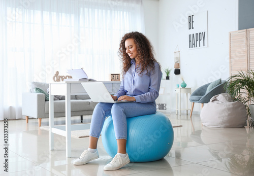 Woman sitting on fitness ba...