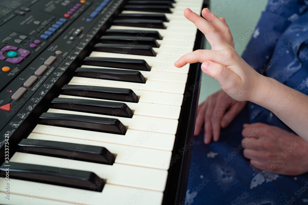 Fototapeta premium little hands black white piano keys synth close-up
