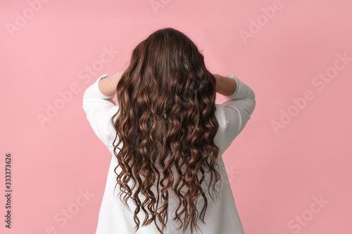 Young woman with beautiful wavy hair on color background photo