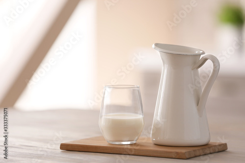 Glass and jug of fresh milk on table