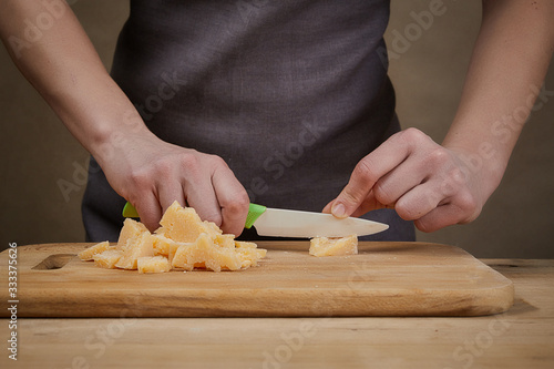 Cooking, food and home concept. Female Hands with knife and cheese