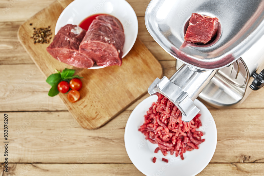 Fresh forcemeat, cutting board with Meat grinder on kitchen table. Top view. Fresh forcemeat, cutting board with Meat grinder on kitchen table. Top view.