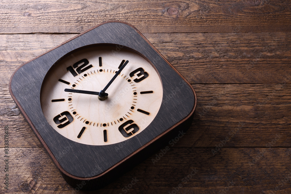 Wooden clock made in hand on wooden background. Close-up. Place for text. Wooden clock made in hand on wooden background. Close-up. Place for text.