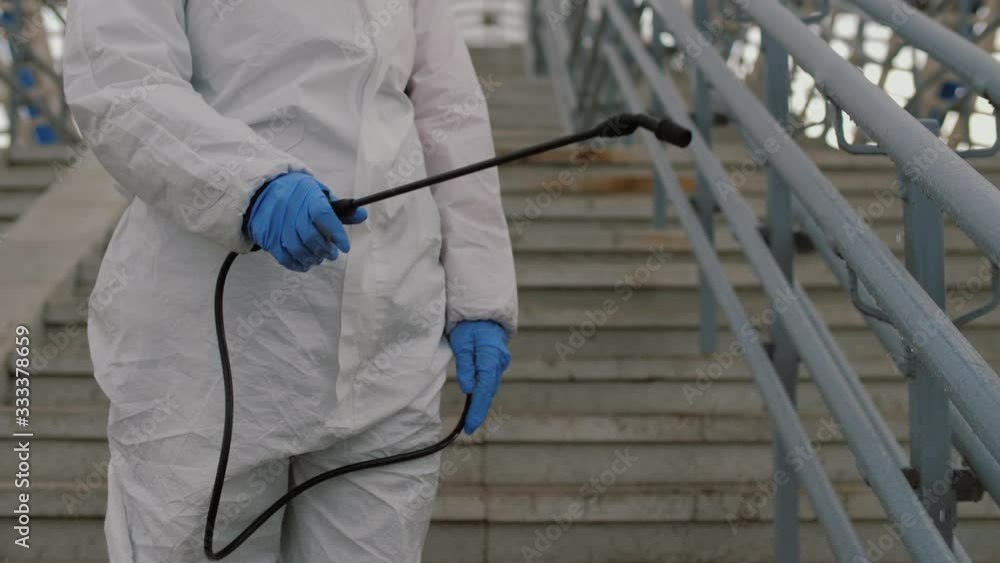 Virologist in protective suit sprays chemicals on handrails in public place, sanitary measures against coronavirus Virologist in protective suit sprays chemicals on handrails in public place, sanitary measures against coronavirus