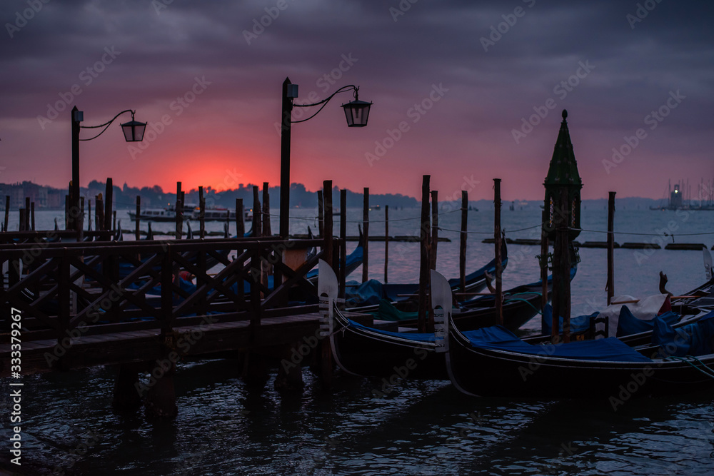 Little pier with gondolas at sunrise. Charming romantic Venice. Travel and rest
