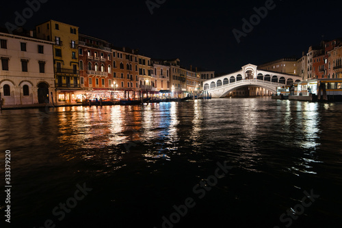 Night view of the city of Rialto and the Grand Canal. Buildings and night light reflect in the water. Venice, Italy