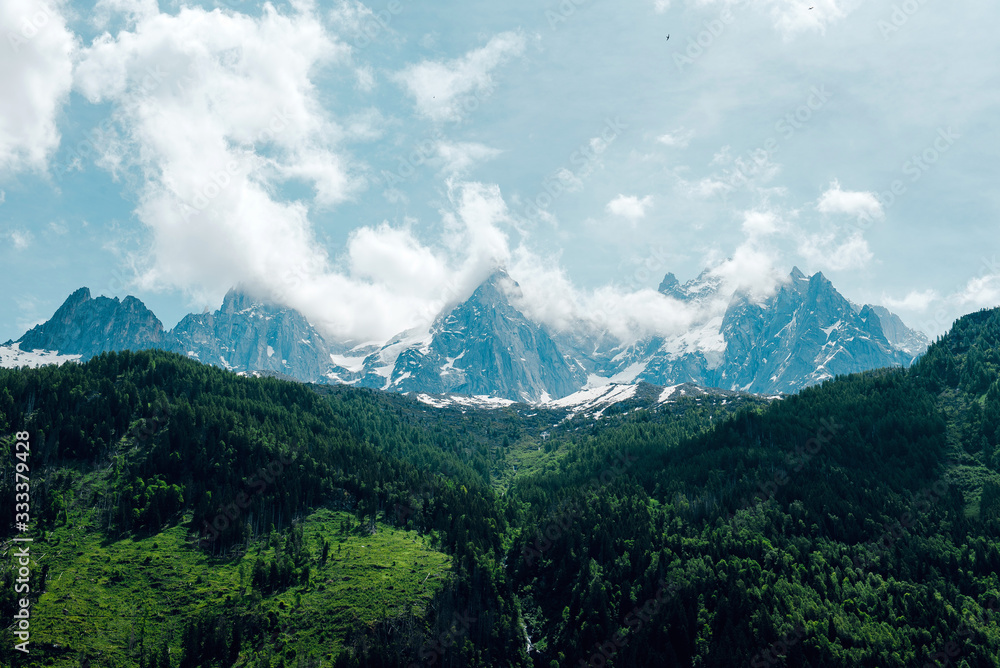 Outdoor landscape in Chamonix. Mountain meadows and snow-capped mountains in clouds. Alps, France