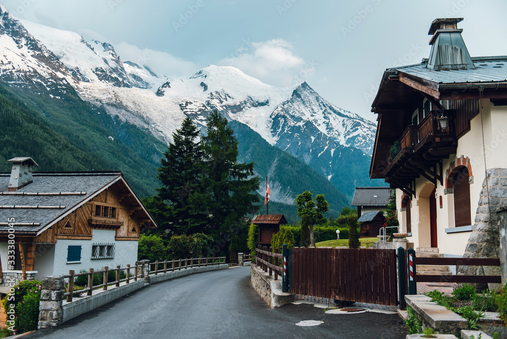 Road with houses overlooking the mountains. Forested and snow-capped mountains in Chamonix. Alps, France