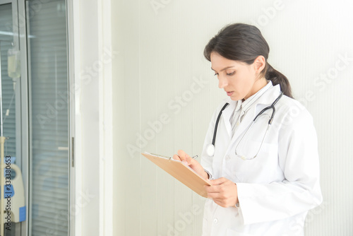 Female doctor filling out medical document. Young woman physician with stethoscope prescribing treatment to patient. Female doctor with pen writing recipe on clipboard in hospital.
