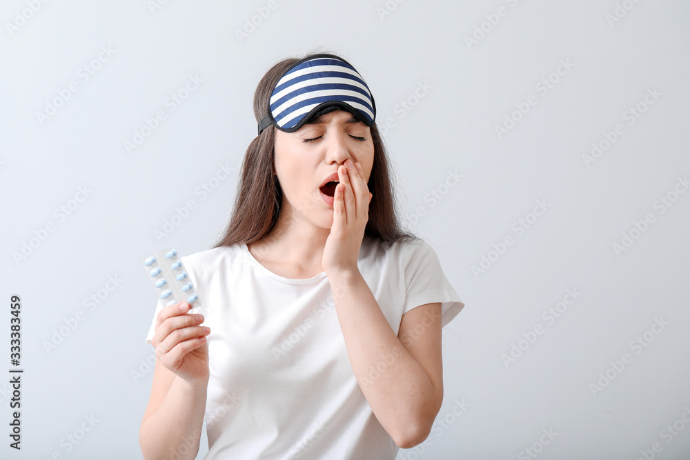 Tired woman with sleeping pills on light background Tired woman with sleeping pills on light background