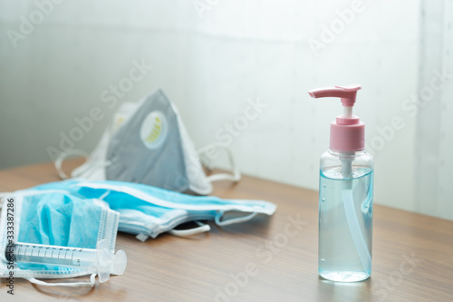 Close-up shot of hand sanitizer gel with medical mask on wooden table. Protection  disease coronavirus 2019-nCoV  hand hygiene and respiratory system. by washing hands frequently  and wearing mask.