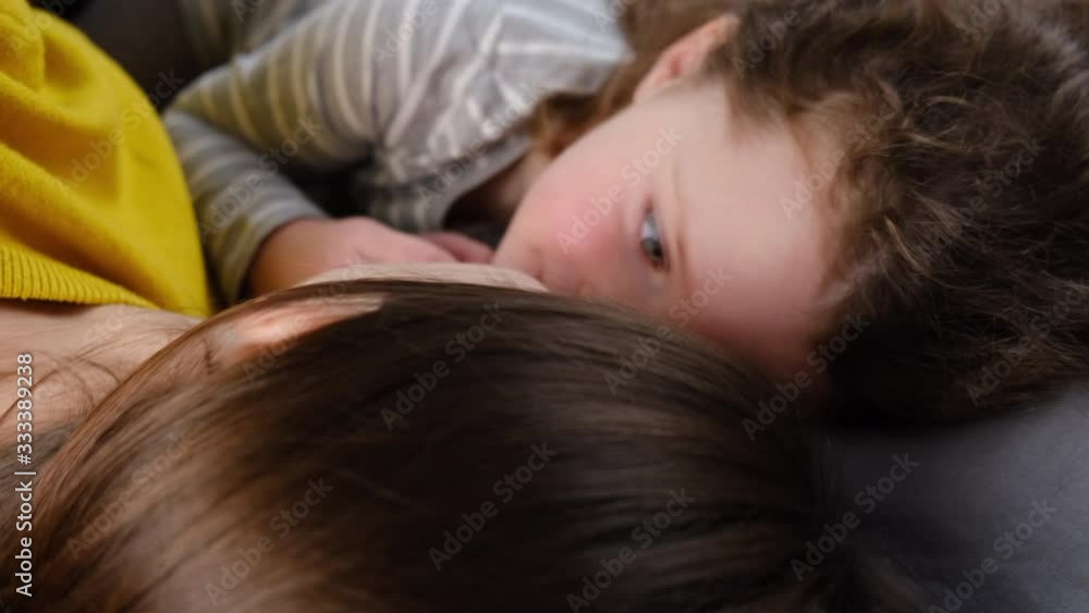 Side view of playful laughing mom and cute small child girl having fun, lying in bed face to face, enjoying active leisure free time in bedroom. Family funny pastime concept.