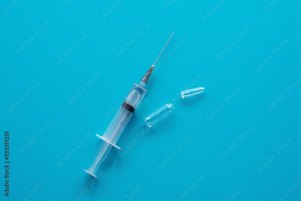 Syringe for injection and ampoule on a blue background. The concept of medicine, healthcare. Flat lay, copy space Syringe for injection and ampoule on a blue background. The concept of medicine, healthcare. Flat lay, copy space