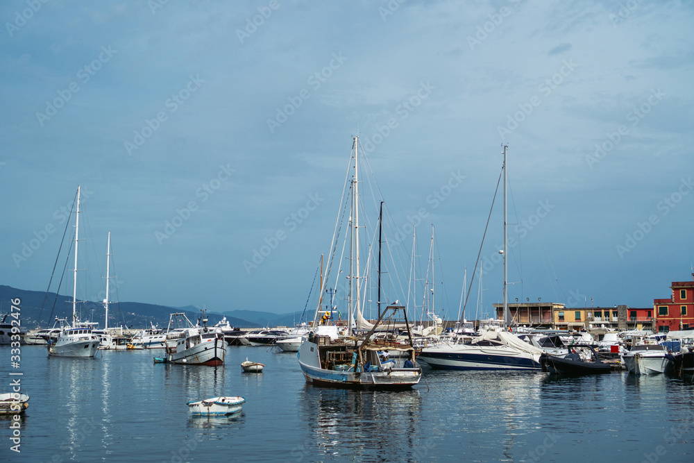 Wide panoramic view of luxury yachts and sailing boats moored in harbor of Santa Margherita Ligure, Italian Riviera. Beautiful mediterranean landscape with cloudy blue sky.