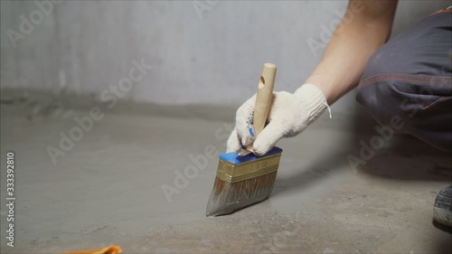 Waterproofing concrete mortar. The master puts waterproofing on a concrete floor with a brush. photo