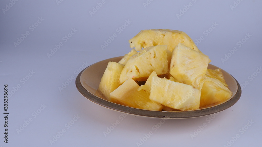 Peeled pineapple in a brown ceramic plate On a white background Peeled pineapple in a brown ceramic plate On a white background