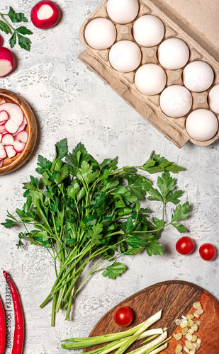 Cooking food background. Eggs, herbs, radishes and tomatoes on a gray concrete background top view, flat lay.