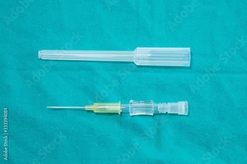 IV catheter with a sterile yellow needle Coupled with a needle sheath placed on a green cloth.