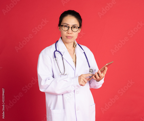 Asian woman doctor using tablet on red background