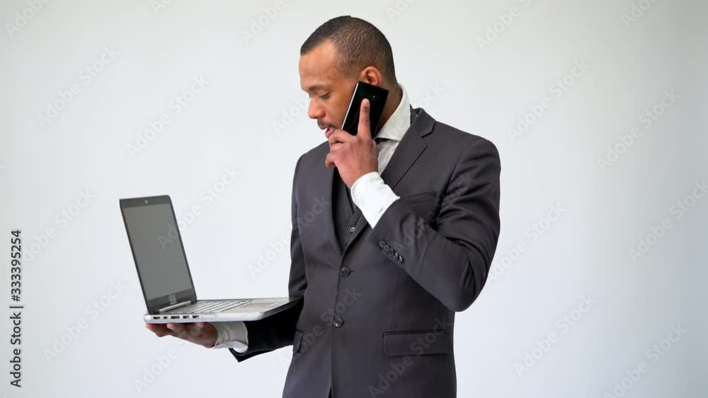 professional african-american business man holding laptop computer and talking on the phone professional african-american business man holding laptop computer and talking on the phone