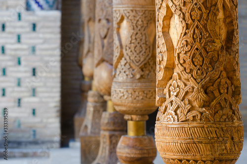 Old wooden pillars covered with carvings, details of decoration. Pahlavon Mahmud mausoleum, Khiva, Uzbekistan, Central Asia.