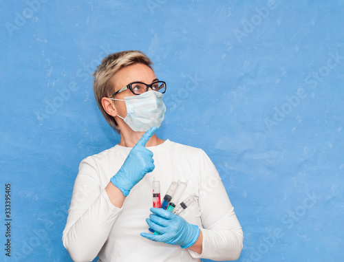 A nurse wears a respiratory mask and gloves warns people about the spread of coronavirus. Blue background, close-up, banner photo