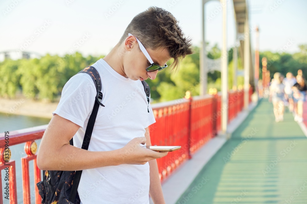 Teen boy 15, 16 years old with sunglasses fashionable haircut with  smartphone Stock Photo