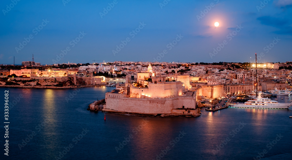 Restored medieval Fort St. Angelo on a peninsula with scenic Grand Harbour views & historical displays at blue hours in Malta