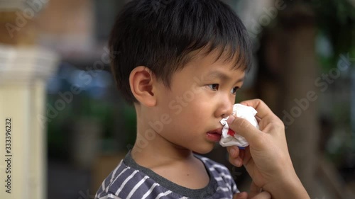 Crying Asian boy about 4 year old with nose bleeding problem being take care by his mother