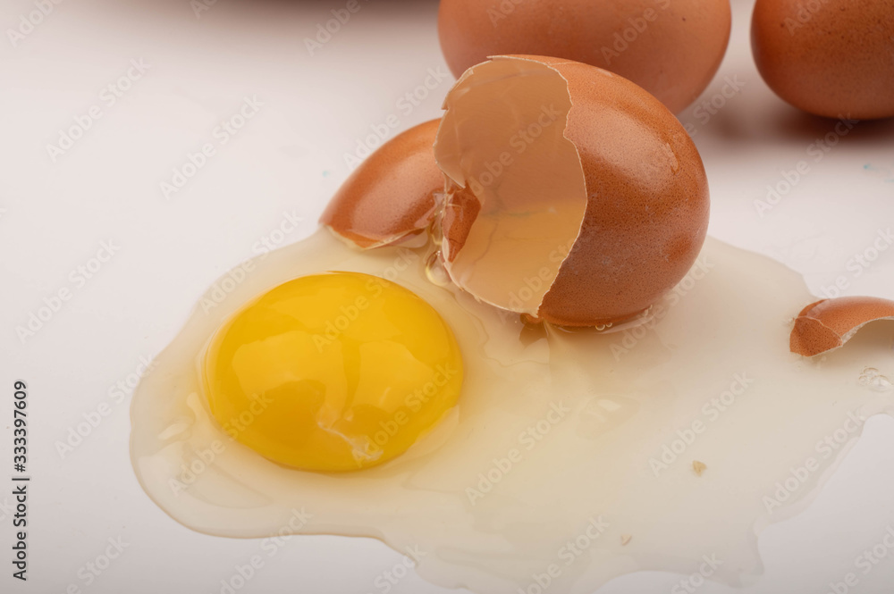 A broken chicken egg and scattered eggs on a white background. Close up.