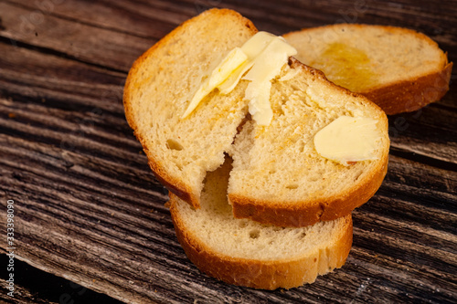 Fresh wheat toast with butter on a wooden background. Close up.
