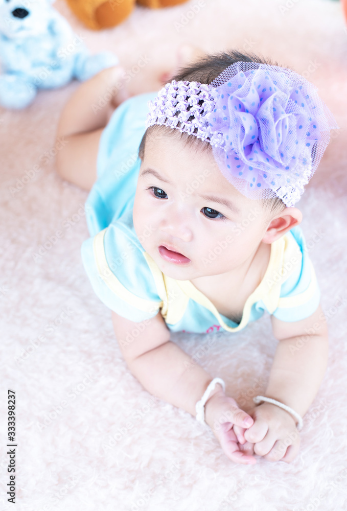 Closeup asian baby infant laying comfortably on bed playing with bear doll on softness cushion,Baby development concept. Closeup asian baby infant laying comfortably on bed playing with bear doll on softness cushion,Baby development concept.