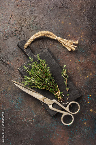 Fresh rosemary spice for tasty meals and scissors on black wooden board