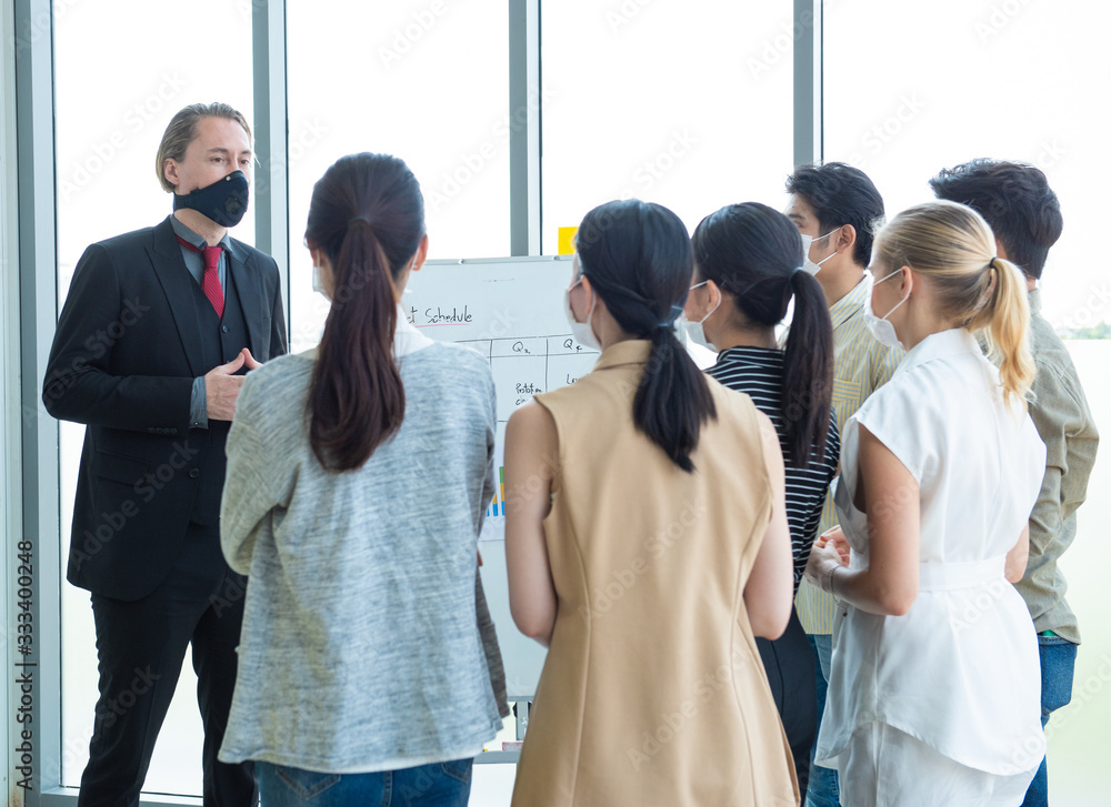 Obraz premium Small business startup multiracial brainstorm meeting with chart paper board everyone mask for covid-19 protection coronavirus flu prevent healthy ideas concept office background.