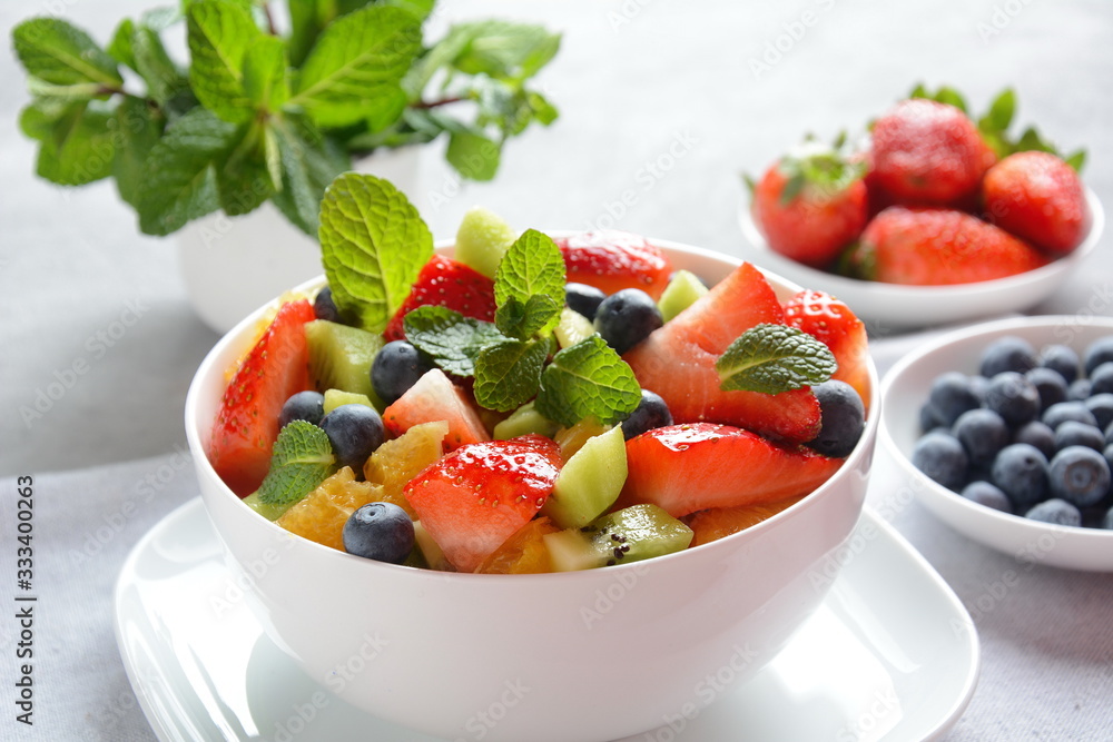 Bowl of healthy fresh colorful fruit salad on wooden background. Top view.Fruit salad with strawberry, blueberry, sweet cherry, kiwi.Vegetarian food concept. Rustic wooden background