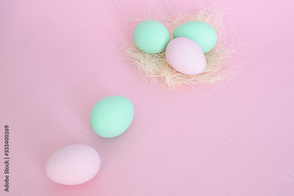 Eggs in nest of pink and mint color, several next to pink background. Easter concept