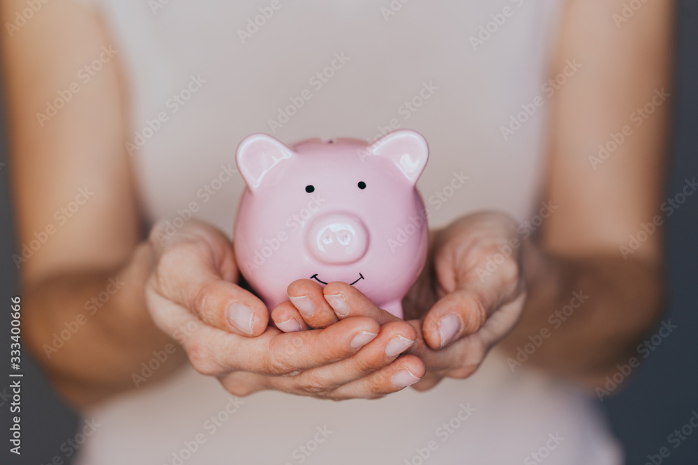female hands protect pink piggy bank, copy space. Concept of saving money or savings female hands protect pink piggy bank, copy space. Concept of saving money or savings