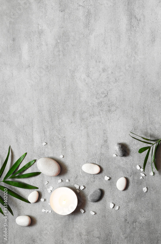 Spa concept on stone background, palm leaves, candle and zen, grey stones, top view.