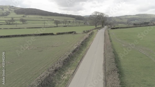 Aerial view of remote idyllic Welsh countryside road in rural farmland meadows orbit right low photo