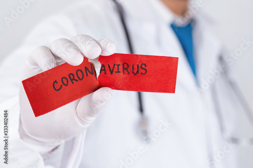 Concept of coronavirus quarantine. MERS-Cov.Novel coronavirus (2019-nCoV).Covid-19,Doctor with a stethoscope Tear the red paper with the word coronavirus. photo