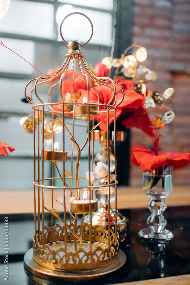 red flower in a wedding decor on a wooden table in a gold stand with candles in a candlestick