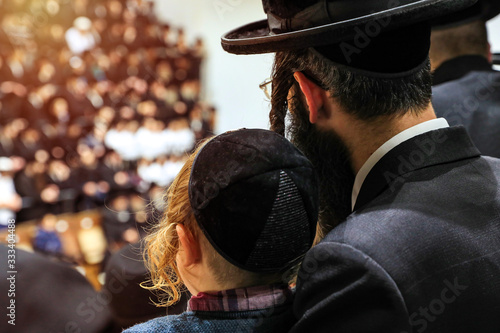 Fototapeta Orthodox pilgrims of Hasidim listen to their rabbi during mass prayer in In a synagogue