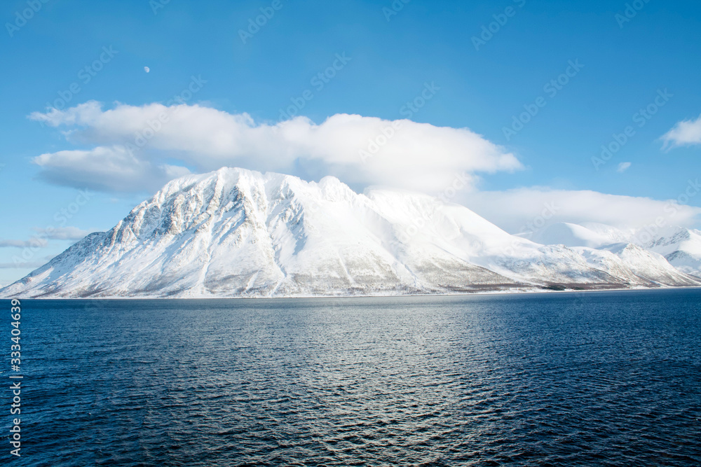 Beautiful blue ocean with a snowy Mountain, clouds and the Moon in the background - Landscape Photography